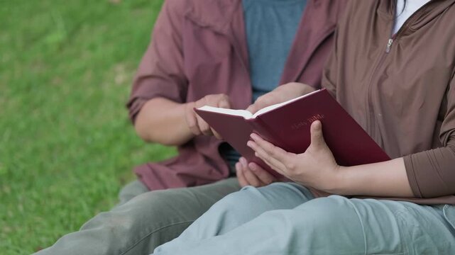 Young Asian people are studying the Bible together amidst lush green nature reflecting the concepts of study religion collaborative learning   mutual support and accessing the true essence of religion