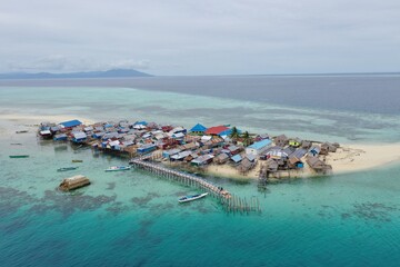 Aerial View of Waterfront Settlement and Wooden Bridge in Tropical Sea © Asril