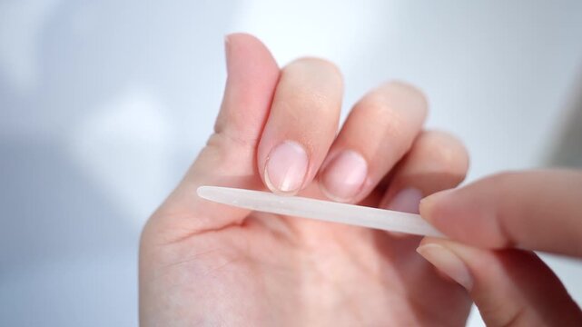close-up of a woman's hands doing a manicure with a nail file