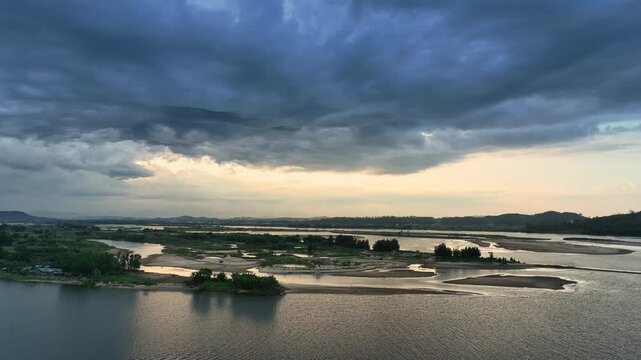 Wide aerial panorama of sandbars and winding channels at the Tra Khuc estuary beneath dramatic evening clouds.