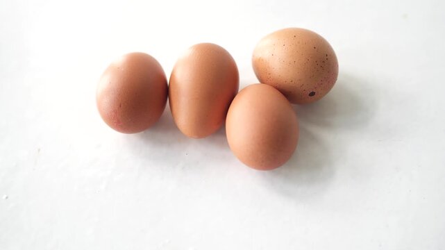 fresh brown chicken eggs resting on a clean white surface in a minimalist composition. The image highlights the simplicity of natural ingredients, making it ideal for cooking, baking, and protein-rich
