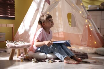 Little girl reading book in wigwam indoors © New Africa