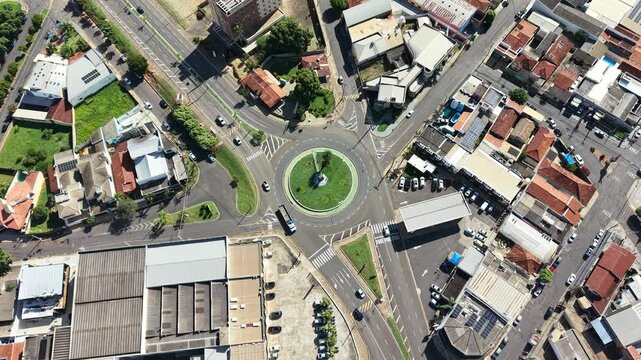 Aerial view of a roundabout intersection with traffic and surrounding urban neighborhood with houses and businesses