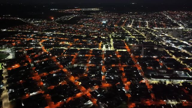 Aerial view of a city at night with glowing streetlights illuminating the urban landscape and residential areas