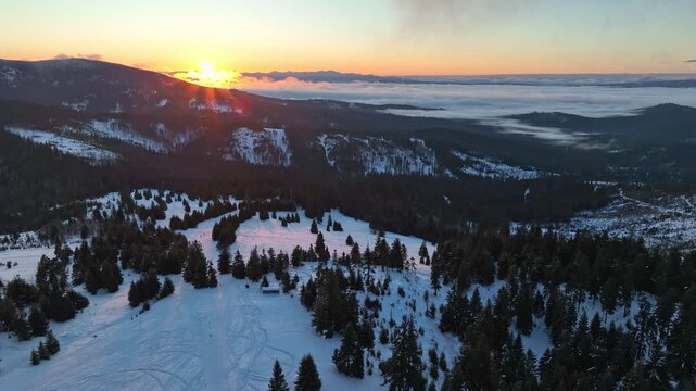 Drone orbit panorama of winter mountain sunrise over snow fields showing distant Mala Fatra and Tatra ranges