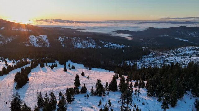 Aerial orbit view of sunlit mountain pasture chalet with tourists silhouettes and distant Tatra peaks at sunrise