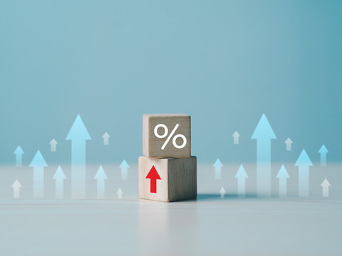 The concept of financial interest rates and mortgage interest rates is represented by wooden blocks with percentage symbols and upward-pointing arrows.