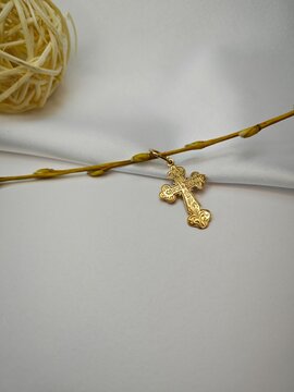 Gold Orthodox cross pendant with engraved text on white background. Religious jewelry and Easter concept