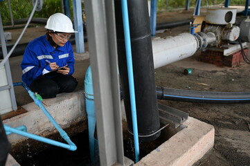 Fototapeta premium Industrial engineer inspecting pipeline systems and equipment inside a water treatment facility. Worker monitoring infrastructure, maintenance processes and utility operations for safe production.