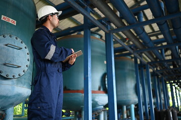 Fototapeta premium Industrial engineer inspecting pipeline systems and equipment inside a water treatment facility. Worker monitoring infrastructure, maintenance processes and utility operations for safe production.