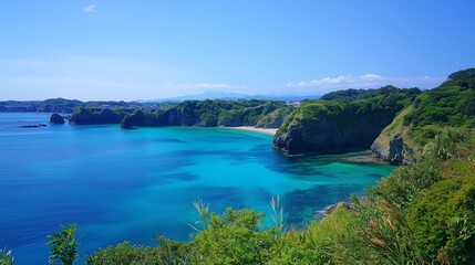 Fototapeta premium High angle panoramic view of a beautiful tropical bay with crystal clear turquoise water and lush green coastal cliffs under a blue sky.