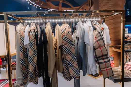 Fashion display featuring various Burberry clothing items on hangers in a modern retail store setting with bright lighting