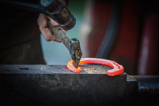 Red hot horse shoe being worked by a farrier. Blacksmith skills. Equestrian. 
