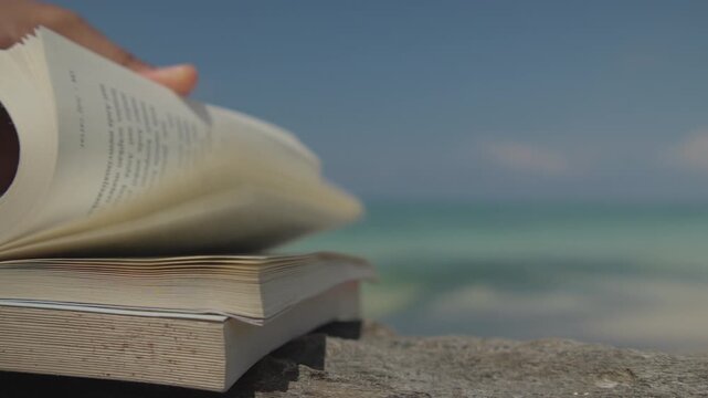 Close Up of an Open Book Resting on a Sandy Beach, Capturing Relaxation, Leisure Reading, Summer Vacation, and a Peaceful Tropical Lifestyle