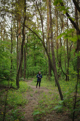 Fototapeta premium Distant view of asian tourist holding water bottle on path in forest 