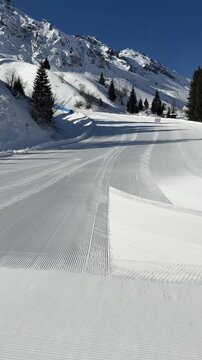 Freshly groomed corduroy snow on an empty ski slope in the Dolomiti Superski region, Italy. Perfectly prepared piste at sunrise with pristine alpine scenery in the Dolomites. Winter sports and mountai