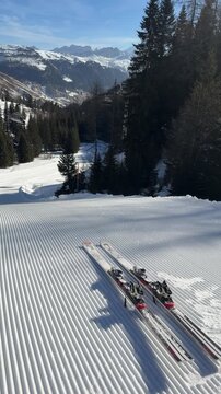 Skis on freshly groomed corduroy snow in the Dolomiti Superski region, Italy. Perfectly prepared ski slope at the start of the day surrounded by alpine scenery. Winter sports and mountain adventure