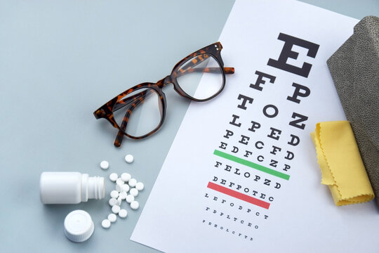 Eye test chart and glasses on blue background