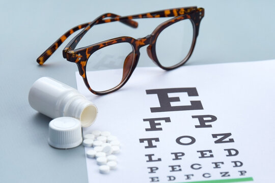 Eye test chart and glasses on blue background