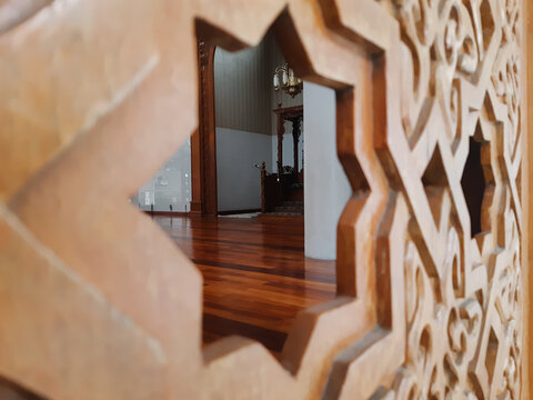 Serene mosque hall and wooden mimbar seen through traditional star geometry cutout