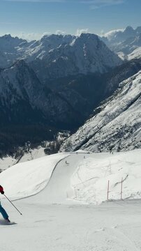 Snowy ski slope in Rocca Pietore, Dolomites, Italy. Panoramic alpine mountain scenery with skiers and dramatic peaks in the Dolomiti Superski region. Winter sports and alpine adventure