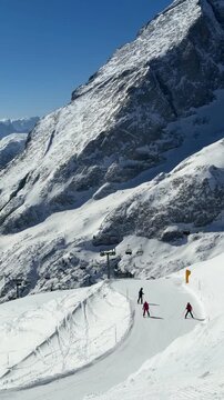 Skiers descending a snowy slope in Rocca Pietore, Dolomites, Italy. Dramatic alpine peaks and pristine mountain scenery in the Dolomiti Superski region. Winter sports and alpine adventure