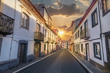 Fototapeta premium Traditional narrow street with old residential houses and balconies in a village on Sao Miguel Island at sunset, Azores, Portugal