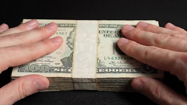 Close up of human hands holding a thick stack of one hundred dollar bills animated video