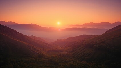 Obraz premium Sunset light casting warm tones on foggy mountain ridges and lush valley terrain