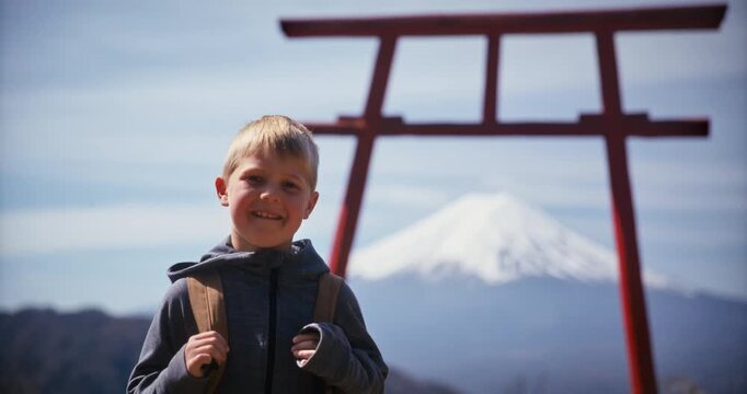 Happy child posing for camera and turning to face torii gate with mt. fuji framed within it - medium, slow motion shot