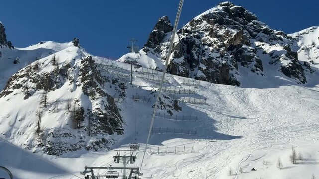 POV view from a chairlift in Livinallongo del Col di Lana, Dolomites. Snow-covered peaks, steep alpine terrain and ski slopes showcase the beauty of the Dolomiti Superski region