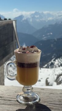 Traditional Italian Bombardino served with whipped cream on a mountain terrace in Dolomiti Superski, Italy. Warm alpine drink overlooking snowy peaks and ski slopes, capturing the cozy apr&egrave;s-ski atmos