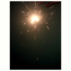 Glowing Firework Sparkler Bursting with Golden Hue Sparks in Dark Room © Joya
