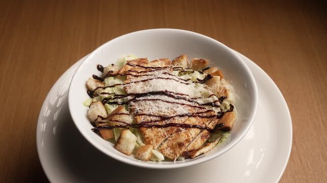 Tasty caesar salad with grilled chicken, croutons, and parmesan cheese served in a white bowl, fa01