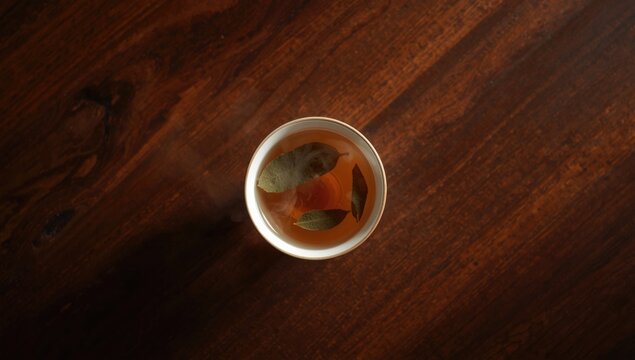 Top view showcasing a cup of bay leaf infused tea on a polished timber table