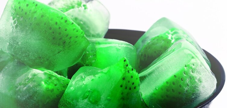 Frozen strawberries in ice cubes with melting water and reflections