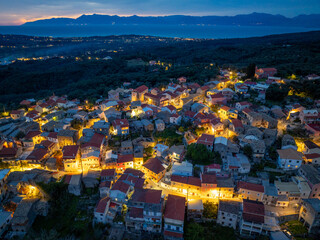 Fototapeta premium Aerial view of Nymfes village edge meeting the dark forest at night, serene travel landscape in Corfu island, Greece