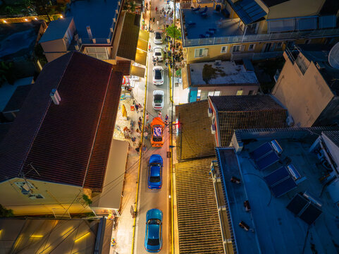 Top Down Aerial Drone View of Narrow Busy Street in Corfu Night with Cars Traffic and Walking Tourists