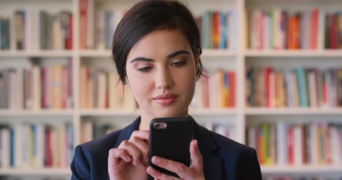 Happy, woman and student in library with phone, social media and email for college business course. Person, typing or thinking at university campus with tech, text message or commerce faculty website