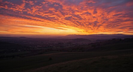 Obraz premium Scenic countryside landscape with distant mountains under colorful sunset sky