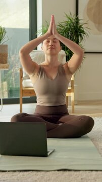 Meditation, namaste and asian woman with laptop in home for mindfulness or spiritual wellness. Calm, female person or inner peace with computer, zen or tutorial for fitness or health guide in house