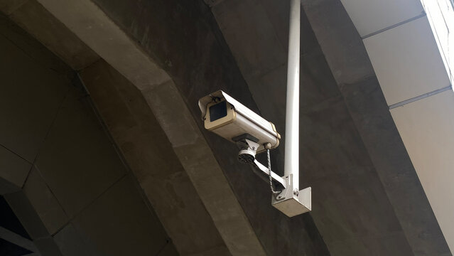 Outdoor CCTV security camera installed on a pole under a concrete bridge structure for public surveillance.