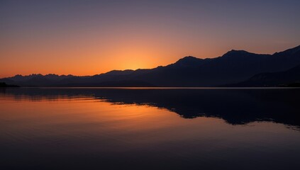 Obraz premium Sunset glow over mountain range mirrored in tranquil water