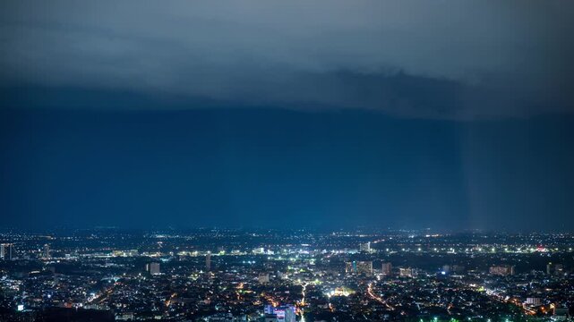 timelapse of night landscape view of Chiang Mai cityscape featuring a rain shaft pouring directly over the ancient pagoda of Wat Chedi Luang temple 
