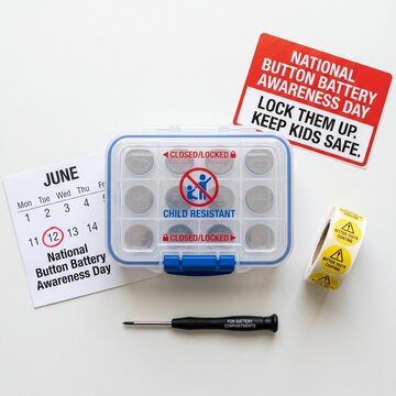 Childproof lockable container with button batteries, safety stickers, screwdriver, and June 12 calendar circled.