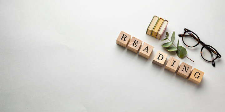 Reading concept with wooden letter blocks, miniature book and glasses promoting literacy, education and learning habit