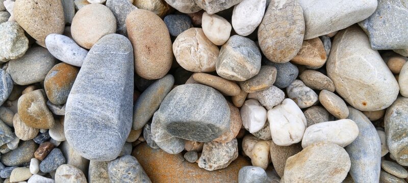 Smooth basalt river rocks tightly clustered together, creating a dramatic charcoal grey backdrop ideal for masculine lifestyle branding materials