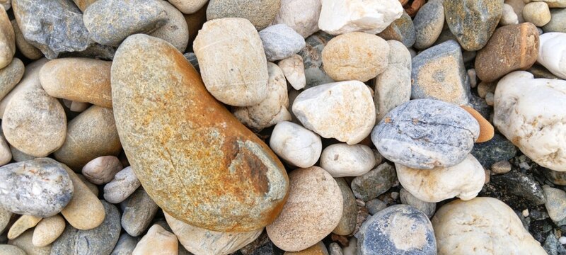 A collection of damp river stones casting soft shadows, providing a natural grounded background texture for eco-friendly product marketing