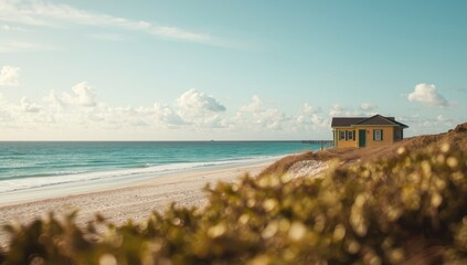 Fototapeta premium Radiant shore house with yellow and green colors on sand near clear turquoise ocean