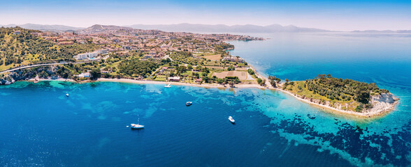 Naklejka premium Kusadasi coastal panorama showing Island and city buildings lining the turquoise Aegean Sea with boats on water